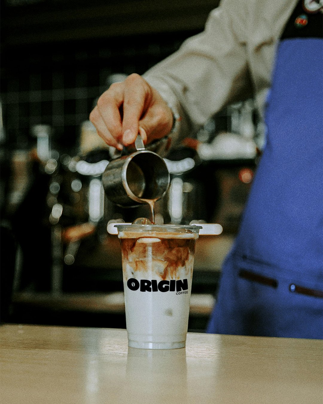 Origin Coffee brand identity - barista pouring a drink into a branded cup